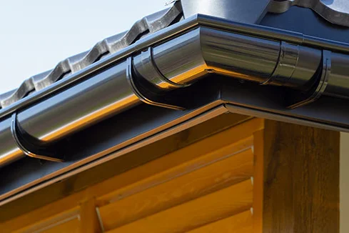 Schwarze Dachrinne an Holzhütte